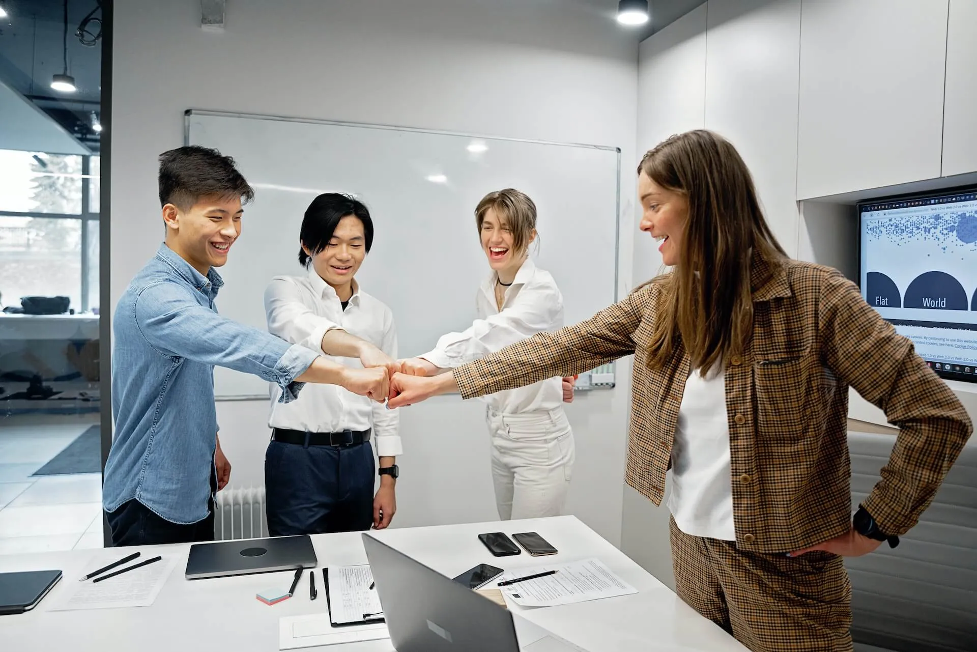 Employees at a meeting fist bumping each other's fists after a successful meeting.