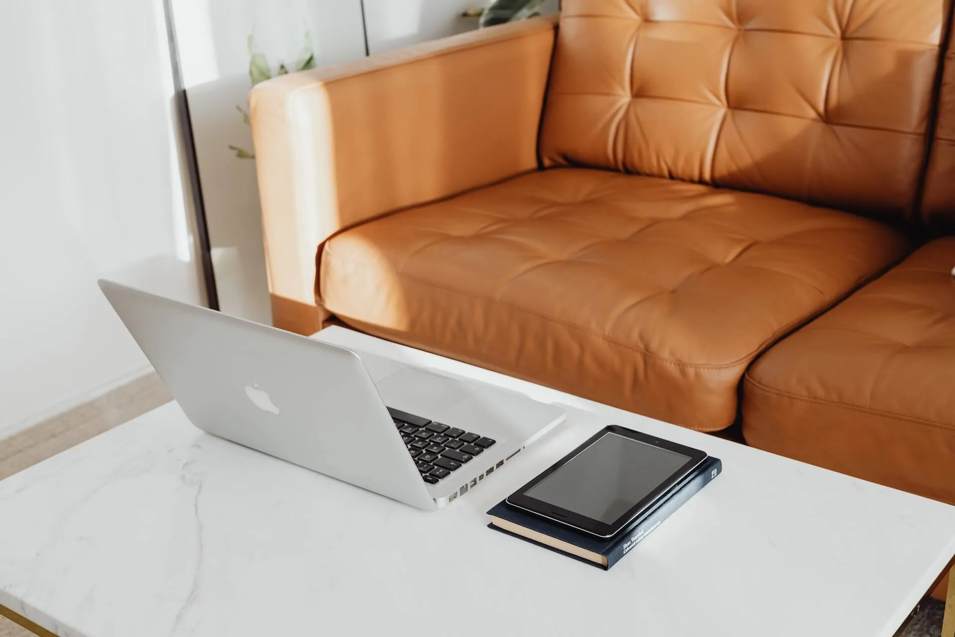A laptop and a tablet on top of a white table.