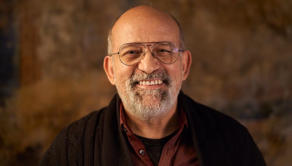 A old man smiling in a room.