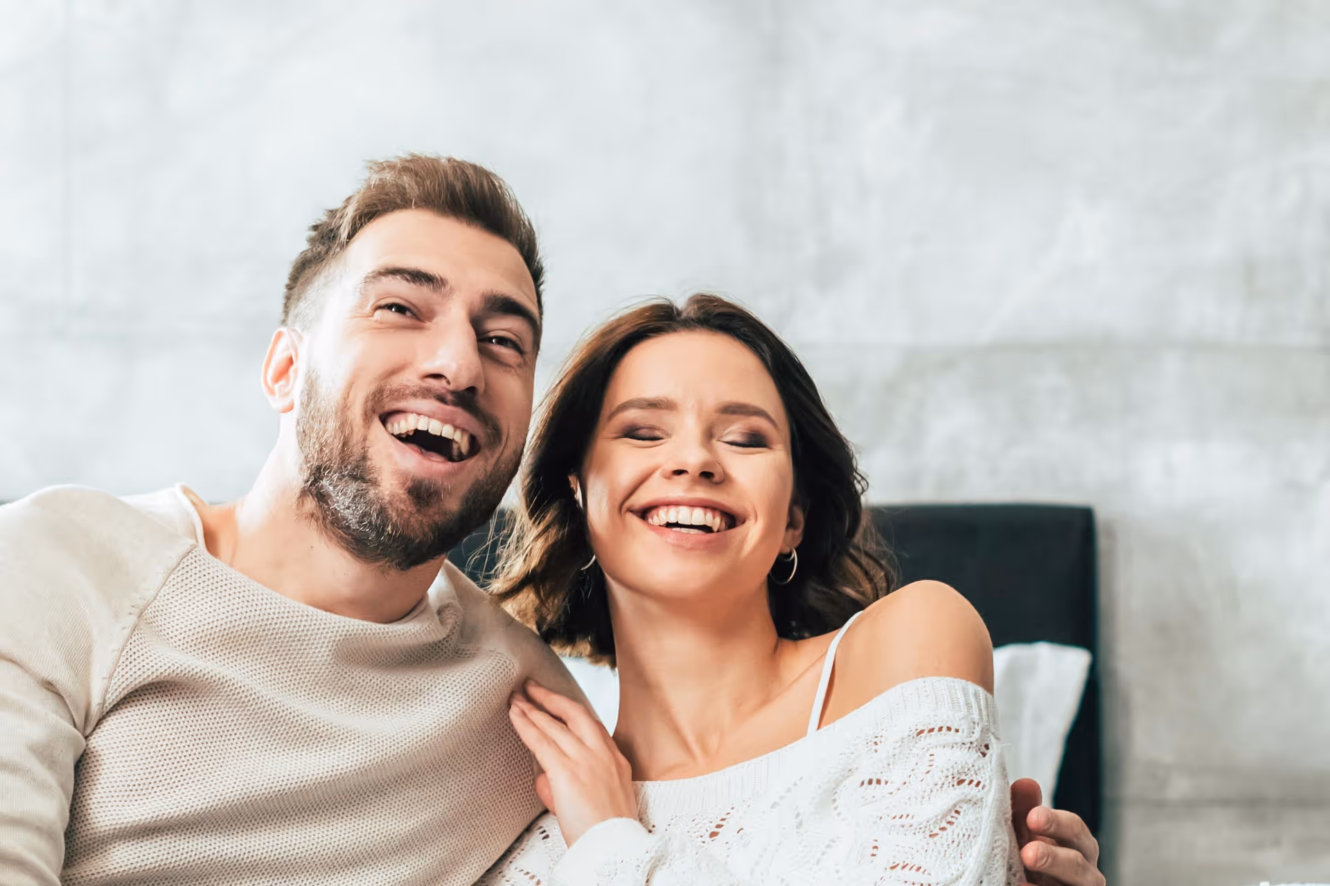 A man and a woman cuddling and smiling together.