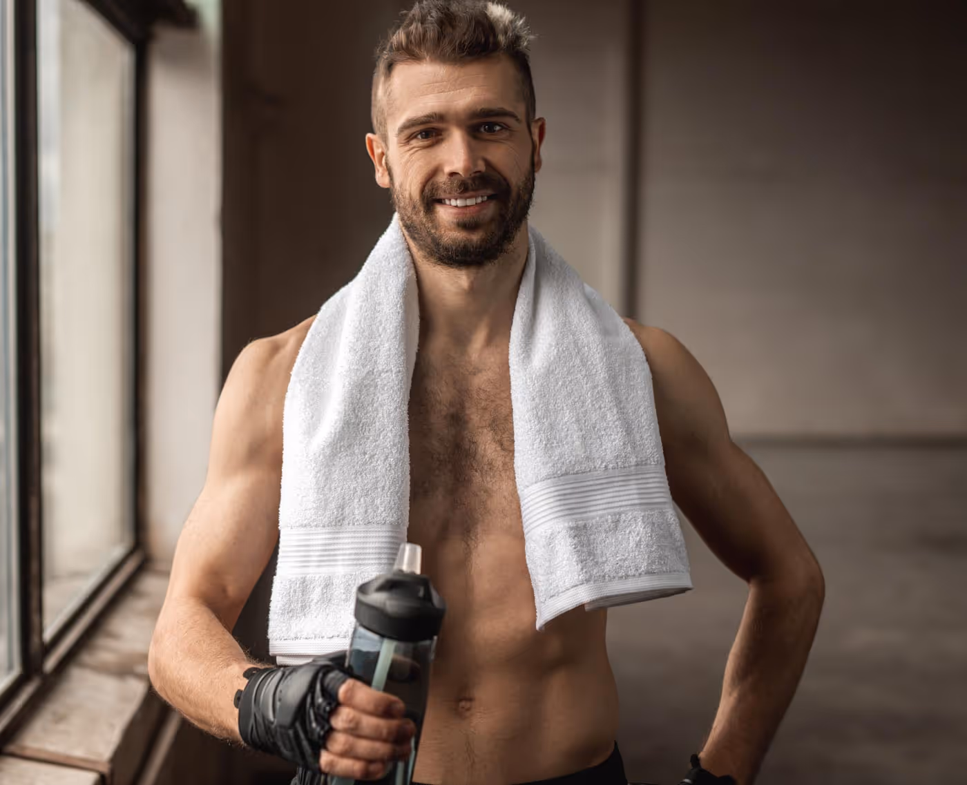 A man at the gym working out and holding a drink in his right hand.