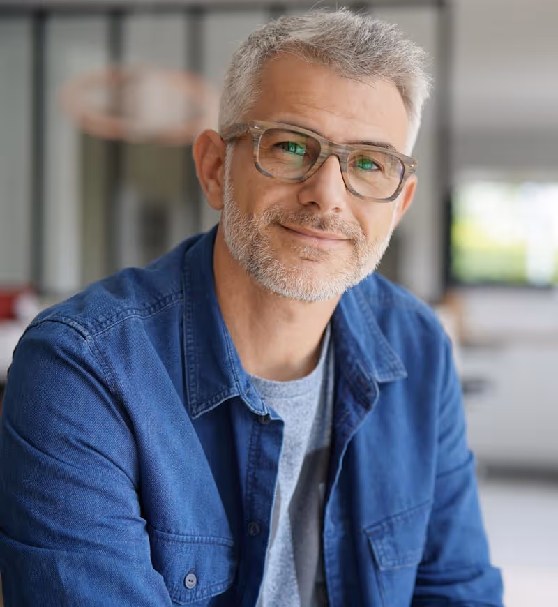 An older man with glasses in his house.