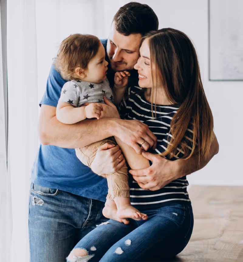 A father and mother hugging their young child.