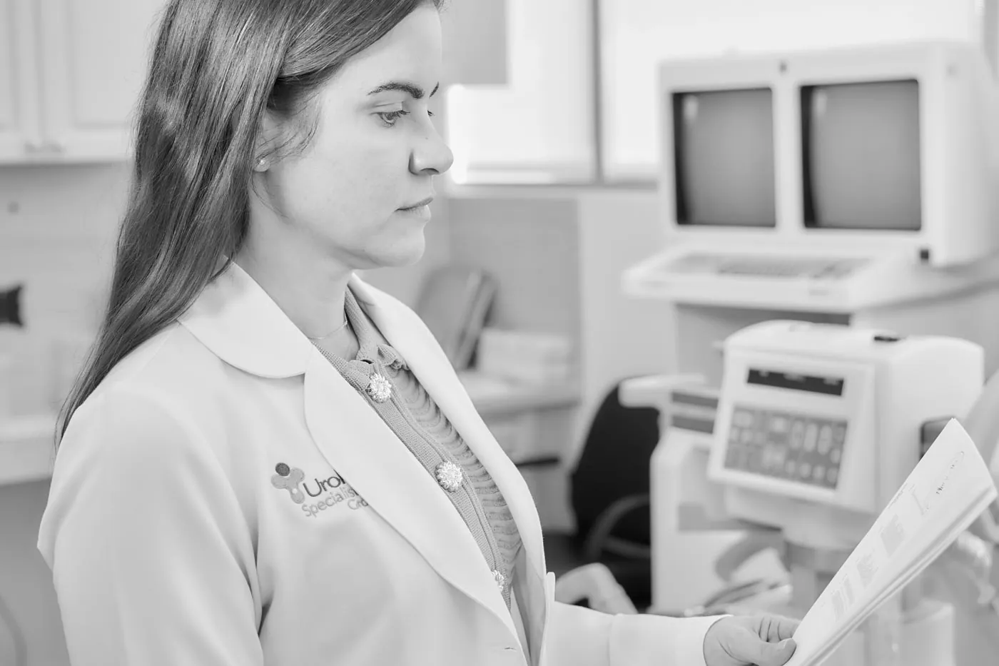 A clinician in a white coat reviewing a patient chart in an exam room.